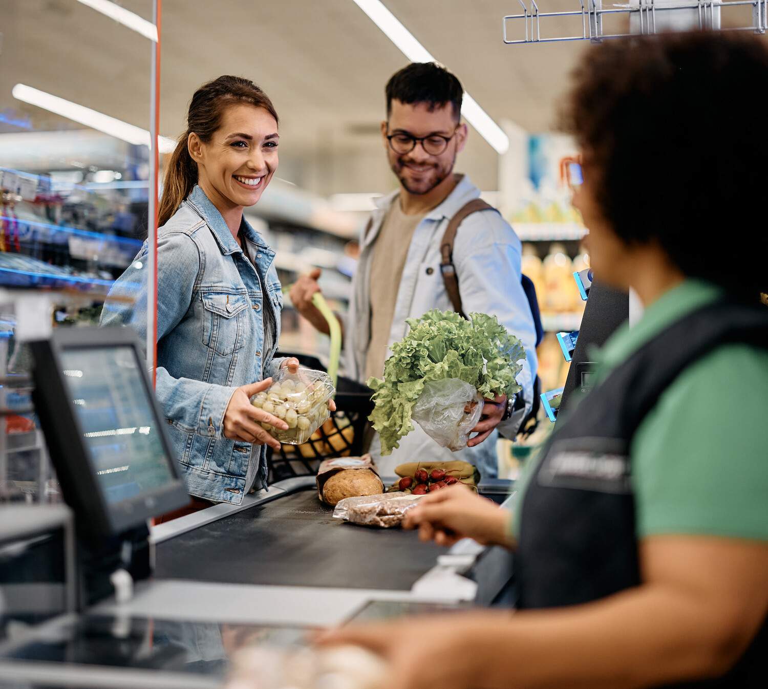 Eine Frau und ein Mann beim Kassieren an der Kasse, sie schauen freudig.